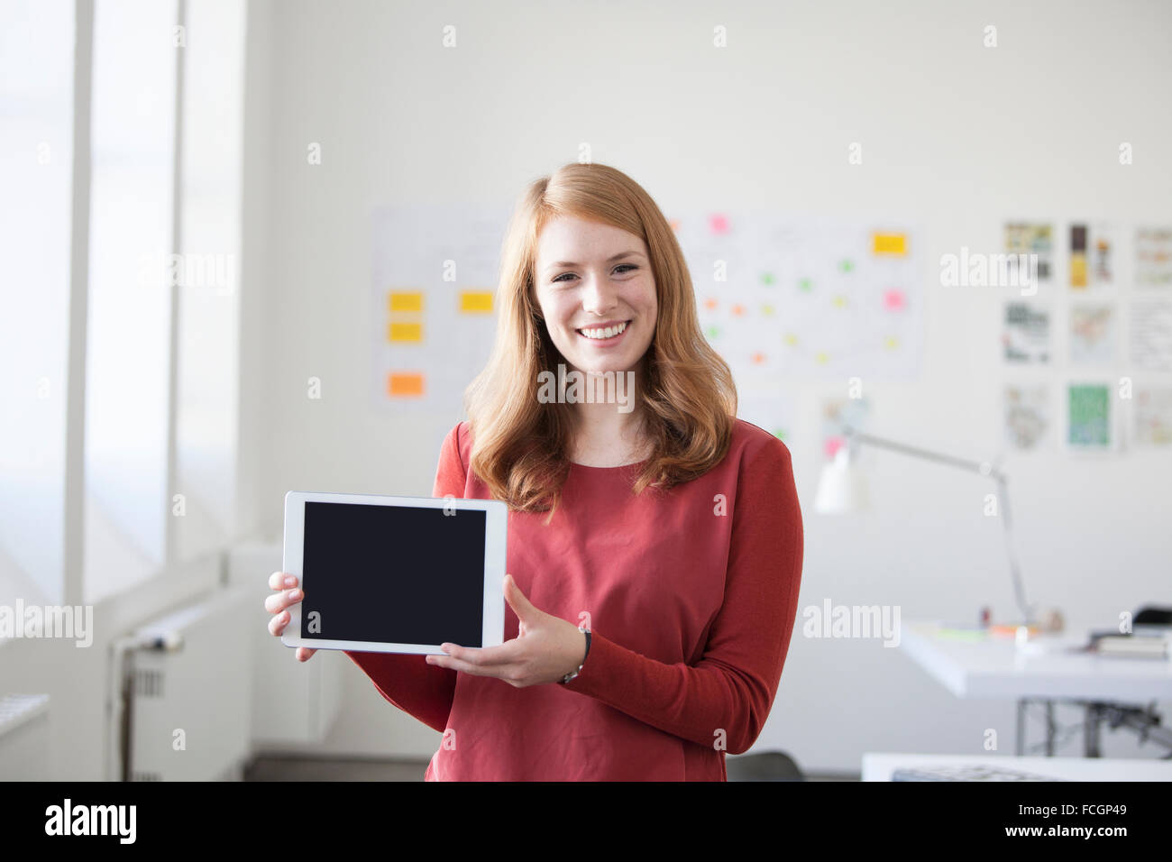 Giovane donna in office holding tavoletta digitale Foto Stock