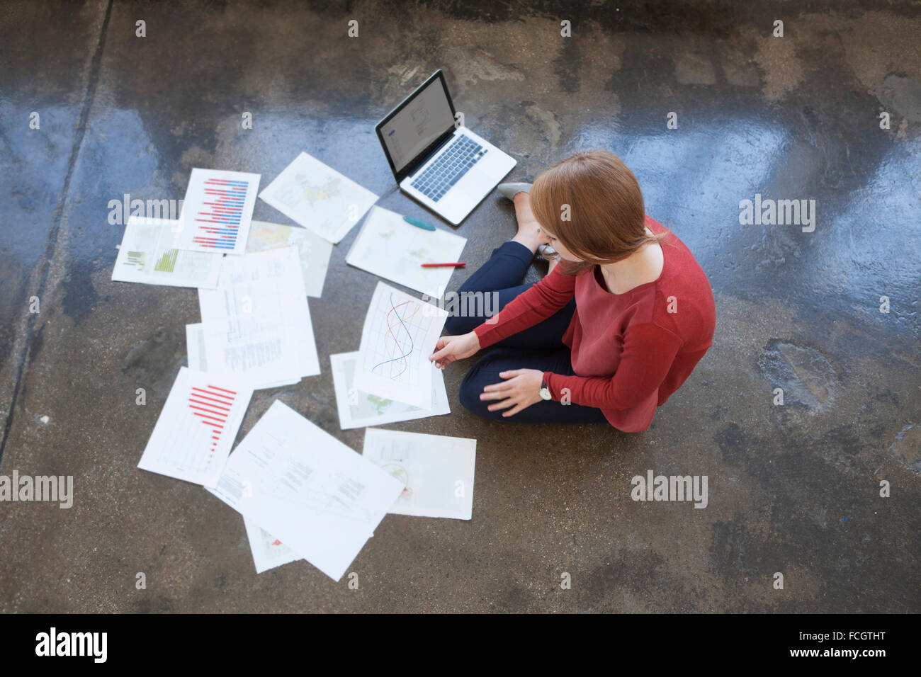 Giovane donna in ufficio seduti sul pavimento lavora attraverso carte Foto Stock