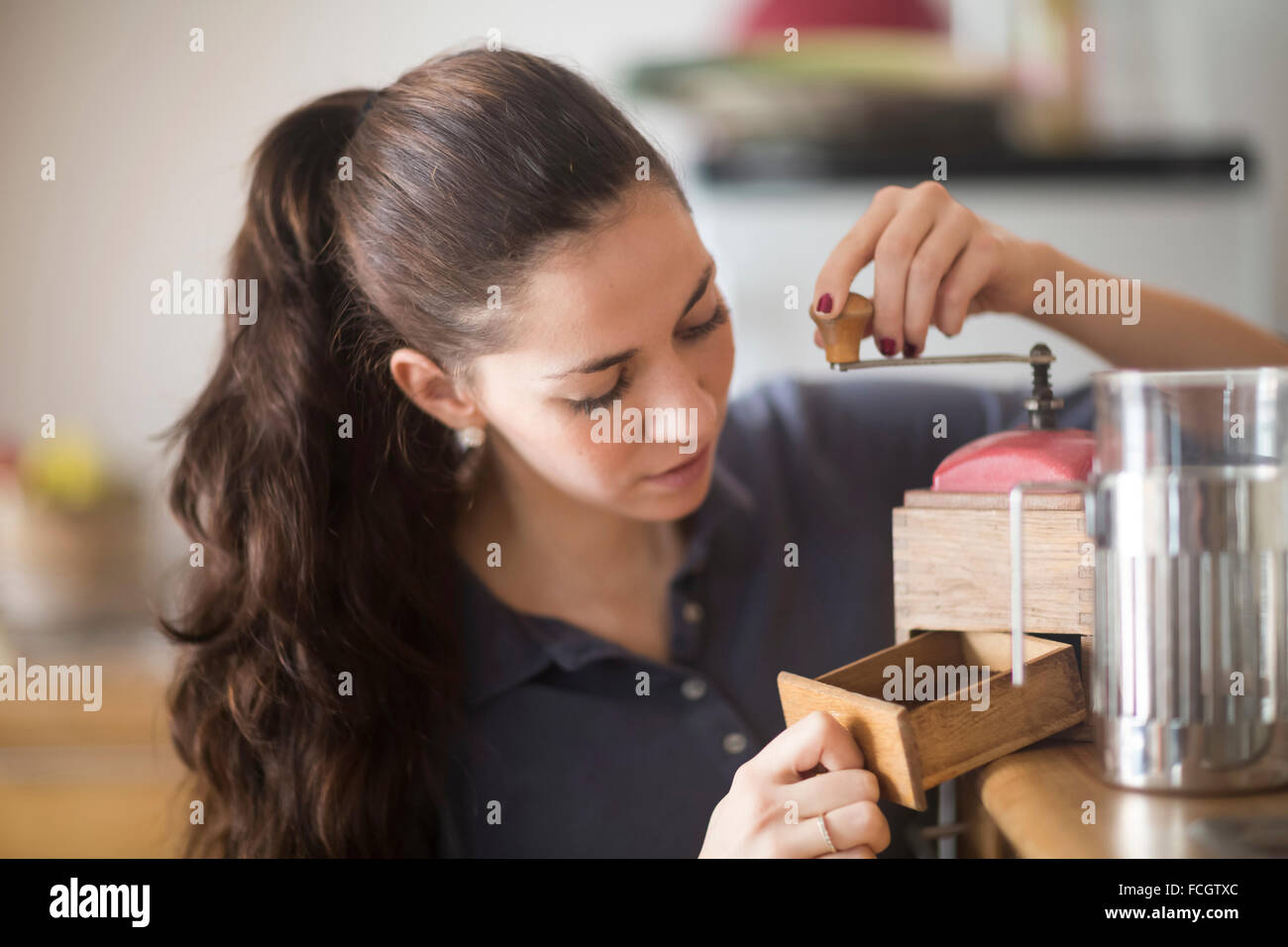 Donna che utilizza coffee mill Foto Stock