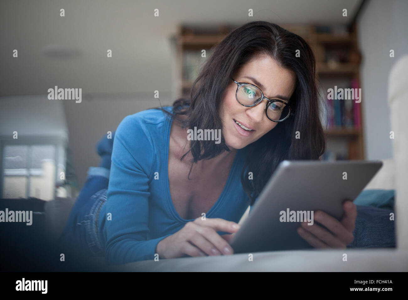 La donna di casa utilizzando tavoletta digitale Foto Stock