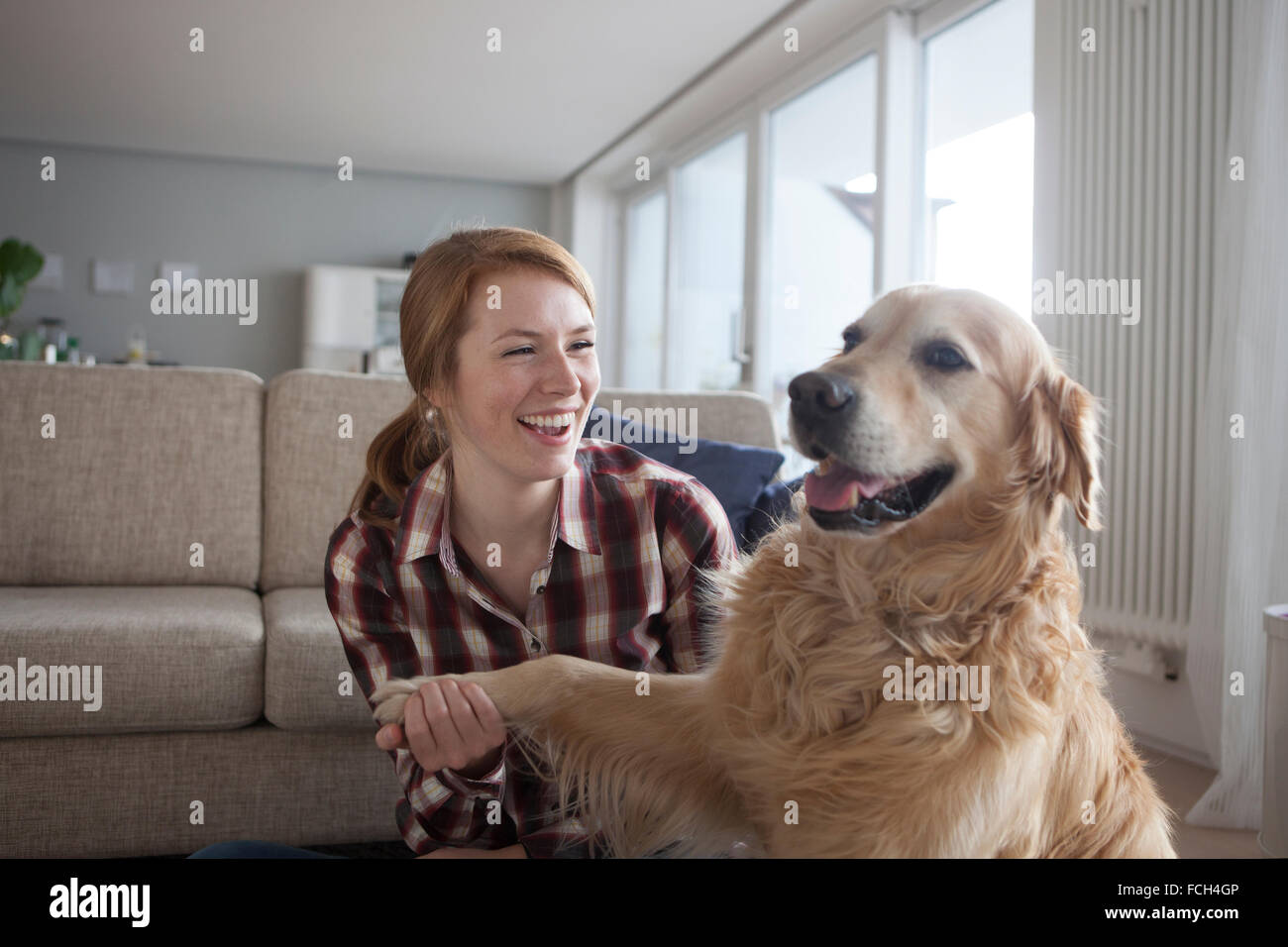 Ritratto di sorridente giovane donna zampa di contenimento del suo cane Foto Stock