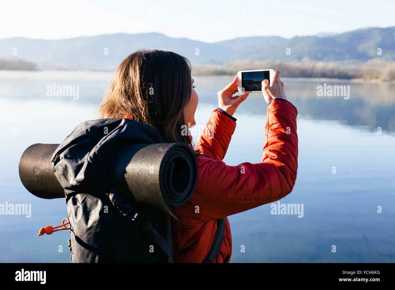 Spagna Catalunya Girona escursionista femminile prendendo un telefono cellulare immagine a un lago Foto Stock