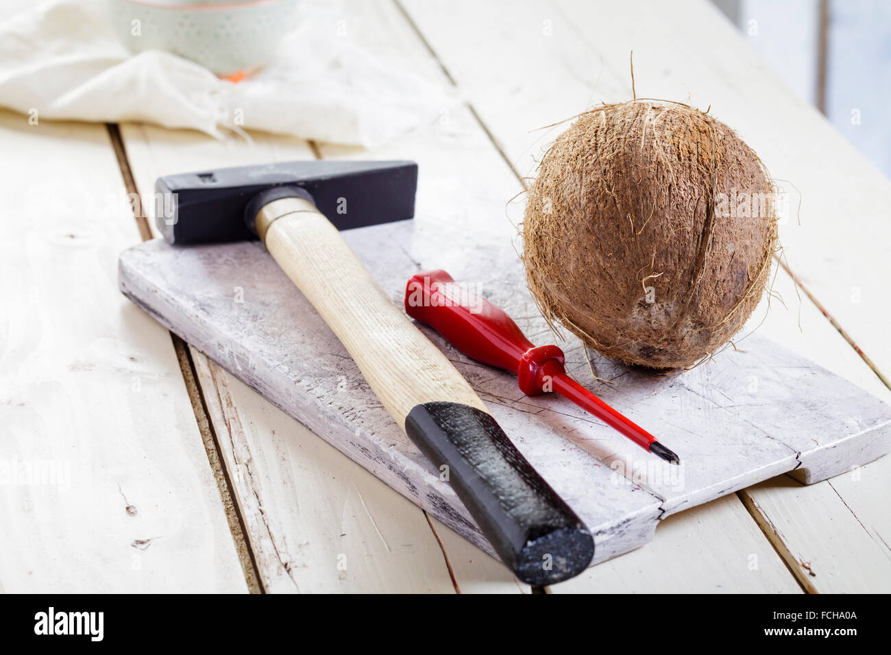 Martello e cacciavite e noce di cocco sul pannello di legno Foto Stock