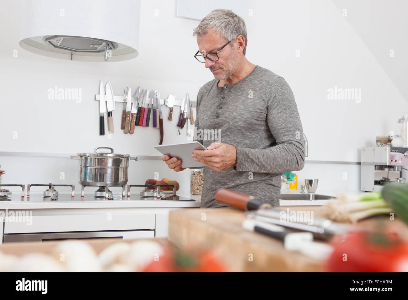 Uomo con tavoletta digitale in cucina Foto Stock