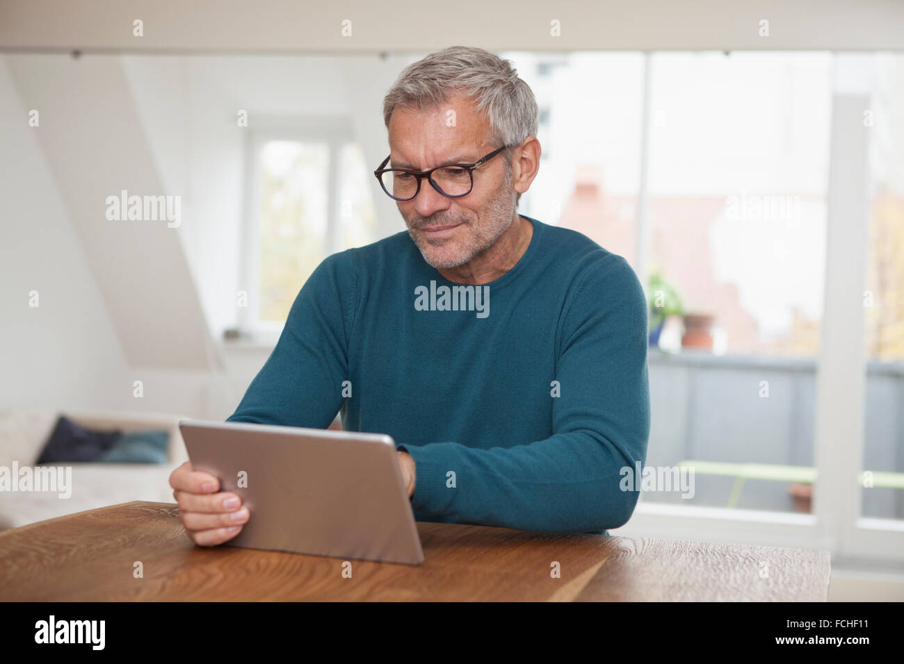 Uomo maturo a casa utilizzando la tavoletta digitale Foto Stock