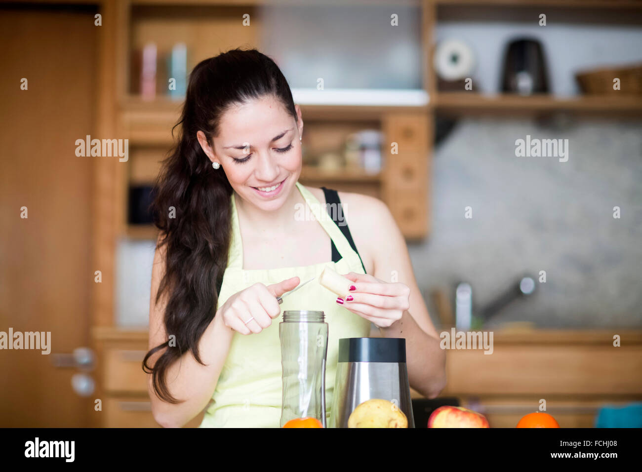 Donna sorridente preparare il cibo nella sua cucina Foto Stock