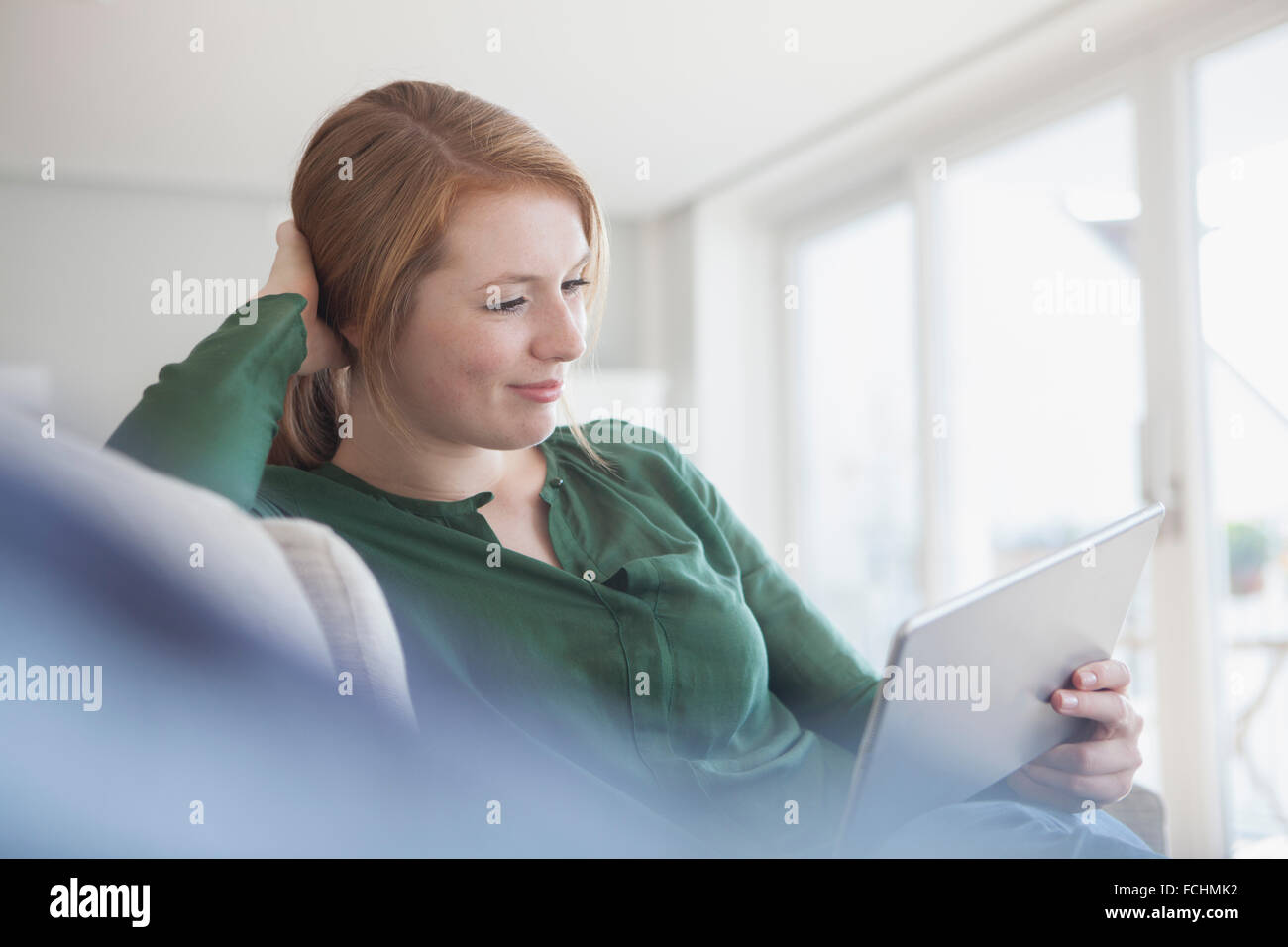 Ritratto di sorridente giovane donna digitale compressa rilassante sul lettino Foto Stock