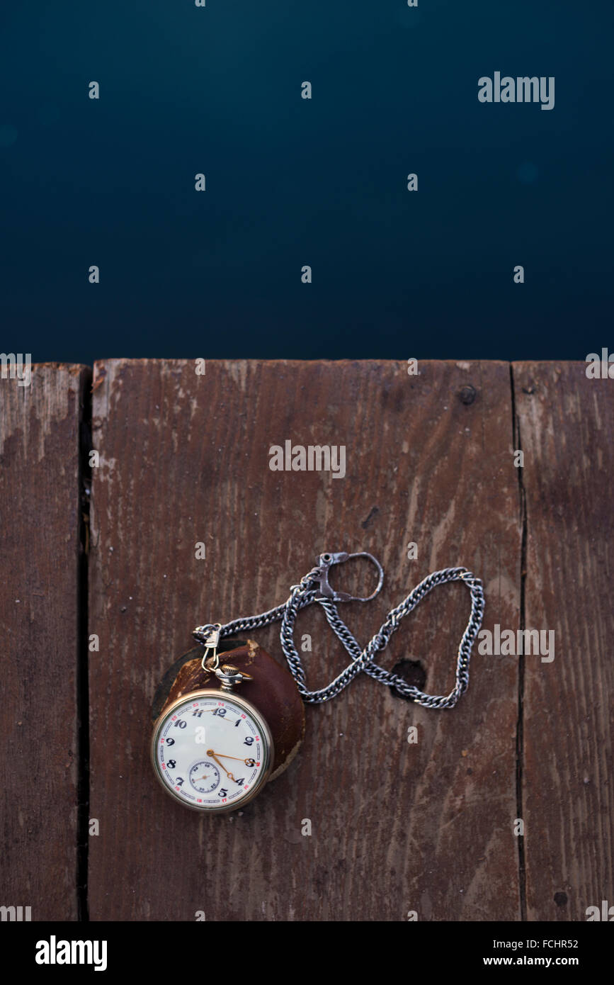 Orologio da tasca e la catena su un pavimento di legno e vicino al bordo delle acque. Foto Stock