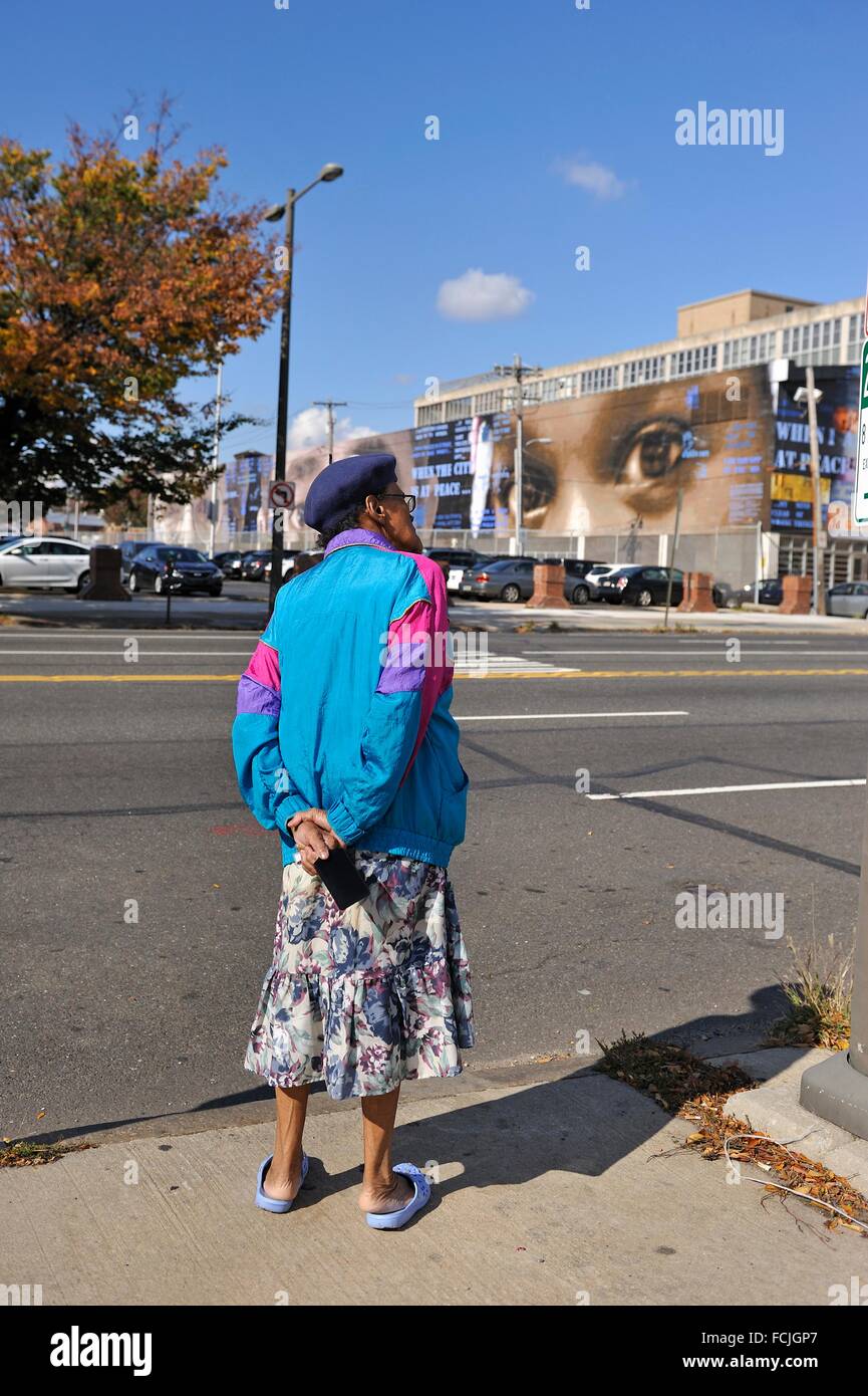 Vista posteriore di una donna con in sottofondo ''tutti a unirvi: visioni di pace ", murale da Jack Ramsdale, pittura murale, programma Foto Stock