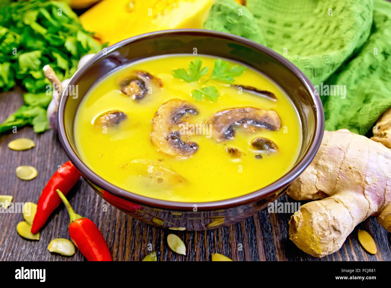 Zuppa di purea di zucca con i funghi in una tazza marrone, verde igienico, prezzemolo, peperoncino baccelli, semi di zucca, lo zenzero, la zucca Foto Stock