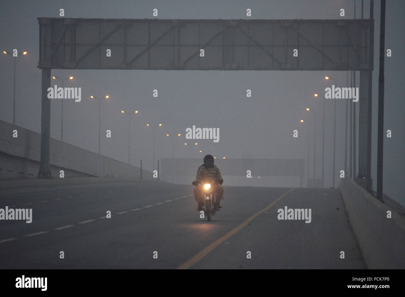 Lahore. 23 gen 2016. Una moto corse nella fitta nebbia in Pakistan orientale di Lahore, 23 gennaio, 2016. La nebbia in corso meteo in molte parti del paese aveva duramente colpite di volo e gli orari ferroviari. Credito: Jamil Ahmed/Xinhua/Alamy Live News Foto Stock