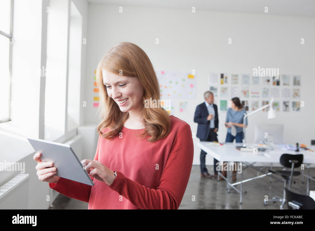 Sorridente giovane donna con tavoletta digitale in ufficio Foto Stock