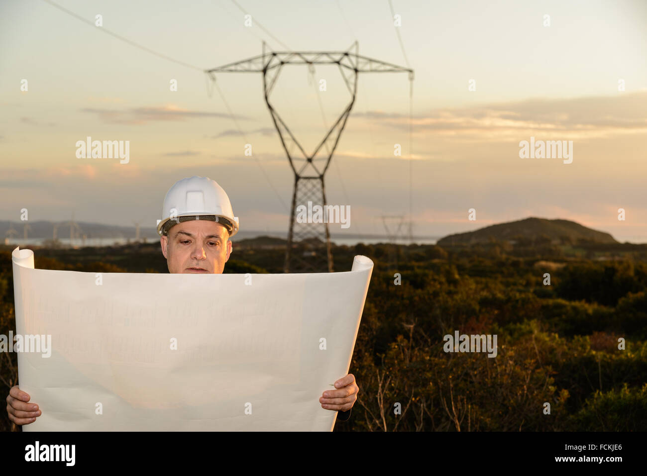 Ingegnere elettrico, controlla la linea di alimentazione e delle turbine a vento al tramonto all'aperto nella campagna Foto Stock