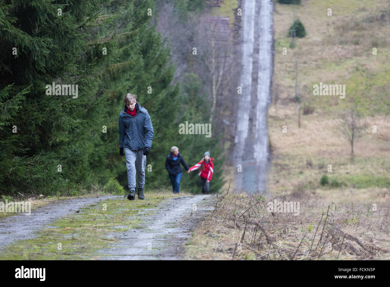 Un ragazzo adolescente conduce il modo su una famiglia a piedi su una ripida collina nella campagna Foto Stock