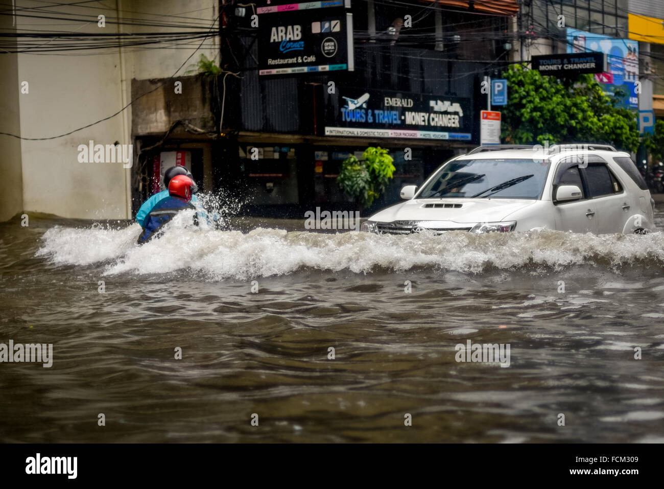 Un conducente e gli automobilisti negoziano i loro veicoli attraverso 40-50 centimetri di acqua alluvionata, dopo una pioggia continua ha lasciato la città di Giacarta allagato. Foto Stock