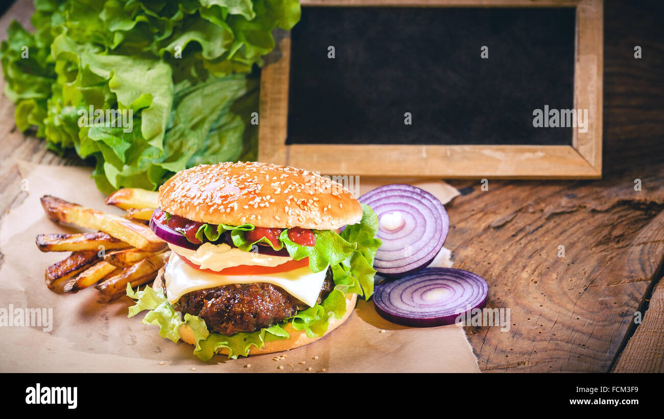 Succosa e fragrante hamburger con patatine fritte fatte in casa sul tavolo vintage. Foto Stock