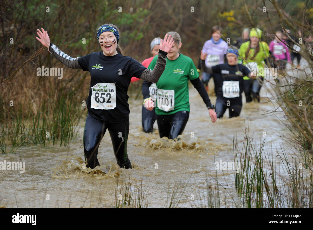 Aldershot, Hants, Regno Unito. 23 gennaio, 2016. Ellen Mumford dà un sorriso alla telecamera come fa il suo modo attraverso i flussi inondate del brutale donne solo 10km gara a lunga valle di Aldershot Hampshire avente per rompere il ghiaccio come il fare tutto intorno al corso . La recente meteo ha reso il brutale 10km fuori strada corso vivere fino al suo nome come nelle pozzanghere e ruscelli dove fino all altezza dei rifiuti in molti luoghi con le prime guide di scorrimento avente per rompere il ghiaccio come sono entrati nell'acqua. Credito: PBWPIX/Alamy Live News Foto Stock