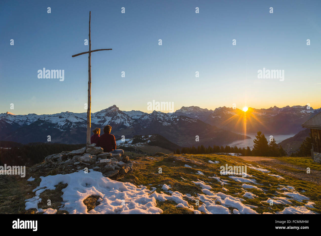 Paio di guardare un tramonto in inverno sulla coperta di neve Glarona montagne in Svizzera da mine antiuomo in punto di vista con una croce latina Foto Stock Paio di guardare un tramonto in inverno sulla coperta di neve Glarona montagne in Svizzera da mine antiuomo in punto di vista con una croce latina Foto Stock