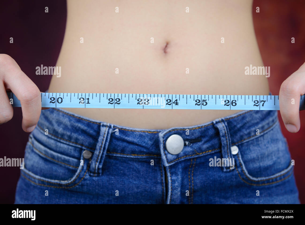 Slim donna asiatica , indossano jeans, misurando la sua forma del corpo, alla cintura, glutei Foto Stock