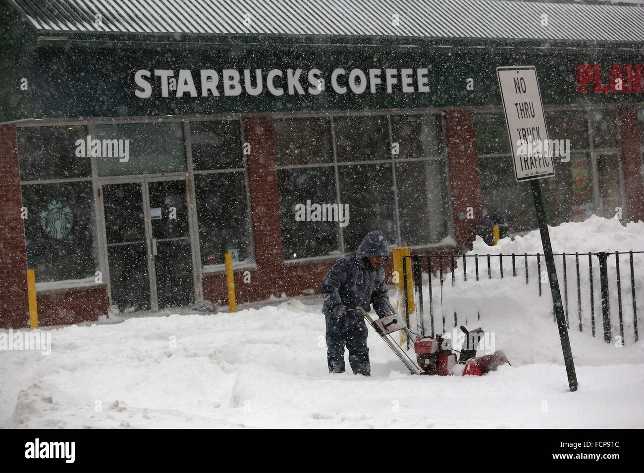 La Staten Island, NY, STATI UNITI D'AMERICA. 23 gen 2016. Un uomo spazzaneve un marciapiede al di fuori di un caffè Starbucks in Staten Island durante la tempesta di neve Jonas. Nel tardo pomeriggio, autobus ha cessato di correre e un divieto di viaggio è stato imposto dal NYPD. Questa mancanza di elica di trasporto molti residenti di Staten Island che aveva preso il traghetto home. Le persone sono state costrette a cercare e raggiungere a piedi la propria destinazione in Blizzard. Nevicata proiezioni per Staten Island sono stati di circa 12-18a, con presenza di raffiche di vento fino a 50 miglia all'ora. Il governatore di New York Andrew Cuomo ha dichiarato lo stato di emergenza per NYC, Long Island e abbassare gli HUD Foto Stock