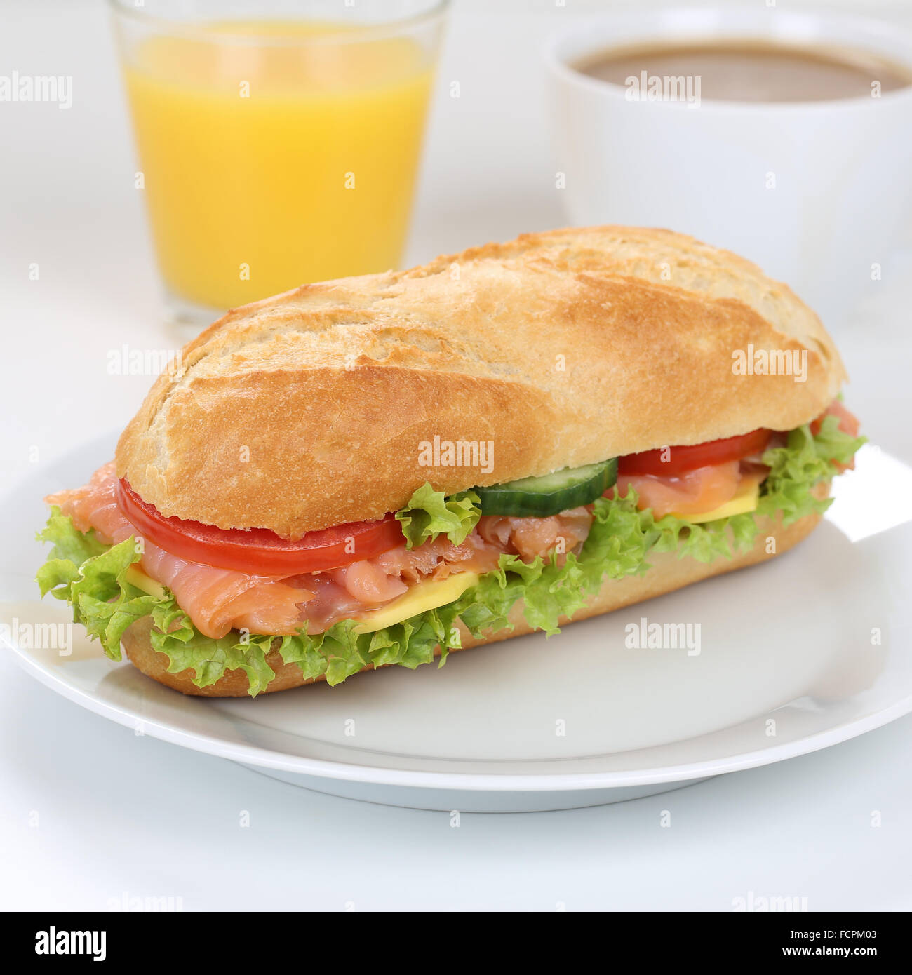 Mangiare sano sub deli sandwich baguette per colazione con salmone pesce, formaggio, pomodori, lattuga e succo di arancia Foto Stock