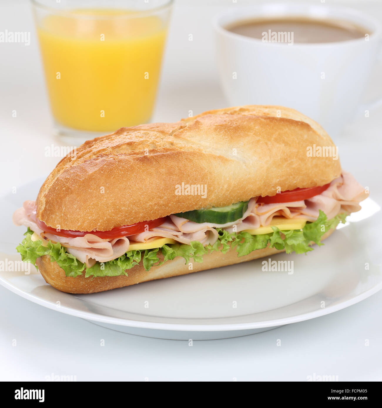 Mangiare sano sub deli sandwich baguette per colazione con prosciutto e formaggio, pomodori, lattuga e succo di arancia Foto Stock
