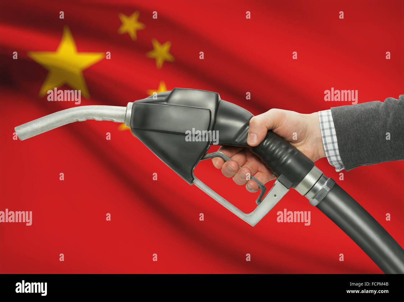 Pompa carburante ugello in mano con bandiera su sfondo - Cina Foto Stock