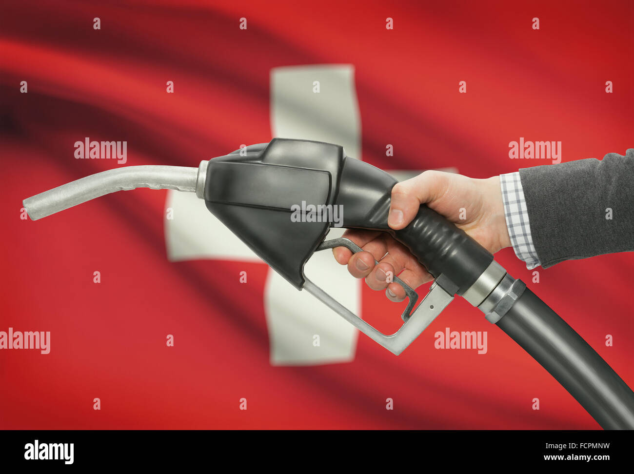 Pompa carburante ugello in mano con bandiera sullo sfondo - Svizzera Foto Stock