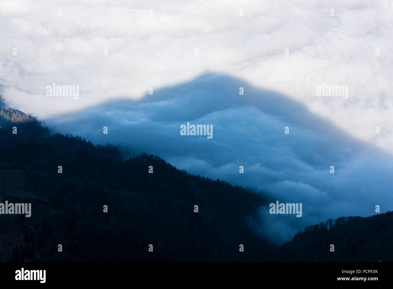 La vetta del monte Rigi, la Svizzera, la colata è la sua ombra scura da sopra le nuvole su un mare di nuvole sotto nella valle. Foto Stock