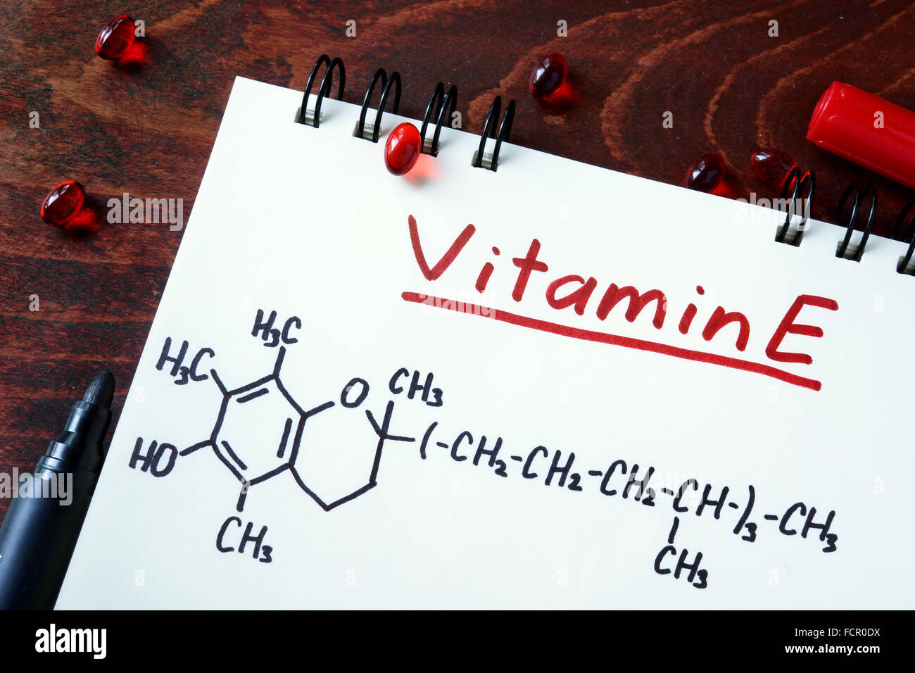 Blocco note con vitamina E e pillole sul tavolo. Foto Stock