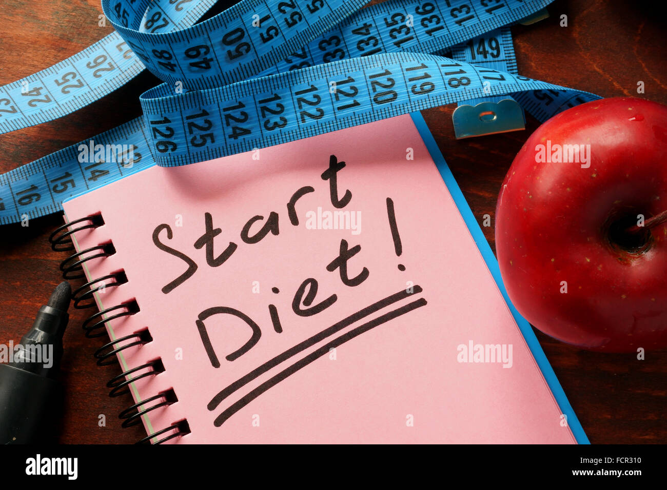 Notebook con le parole inizia la dieta sul tavolo. Foto Stock