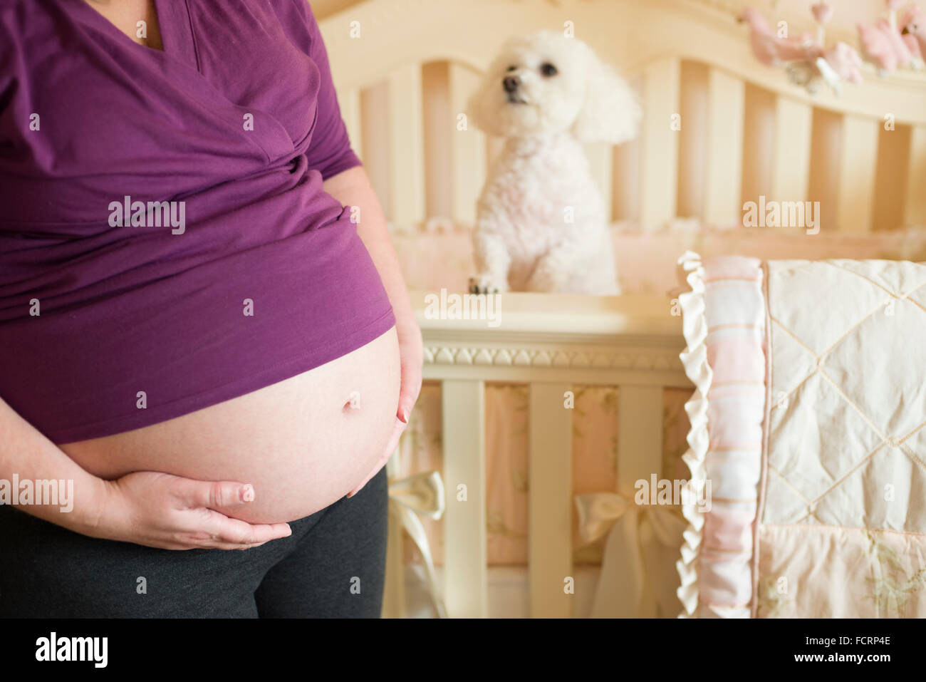 Donna incinta in piedi nella parte anteriore del presepe tenendo il suo bambino pancia Foto Stock