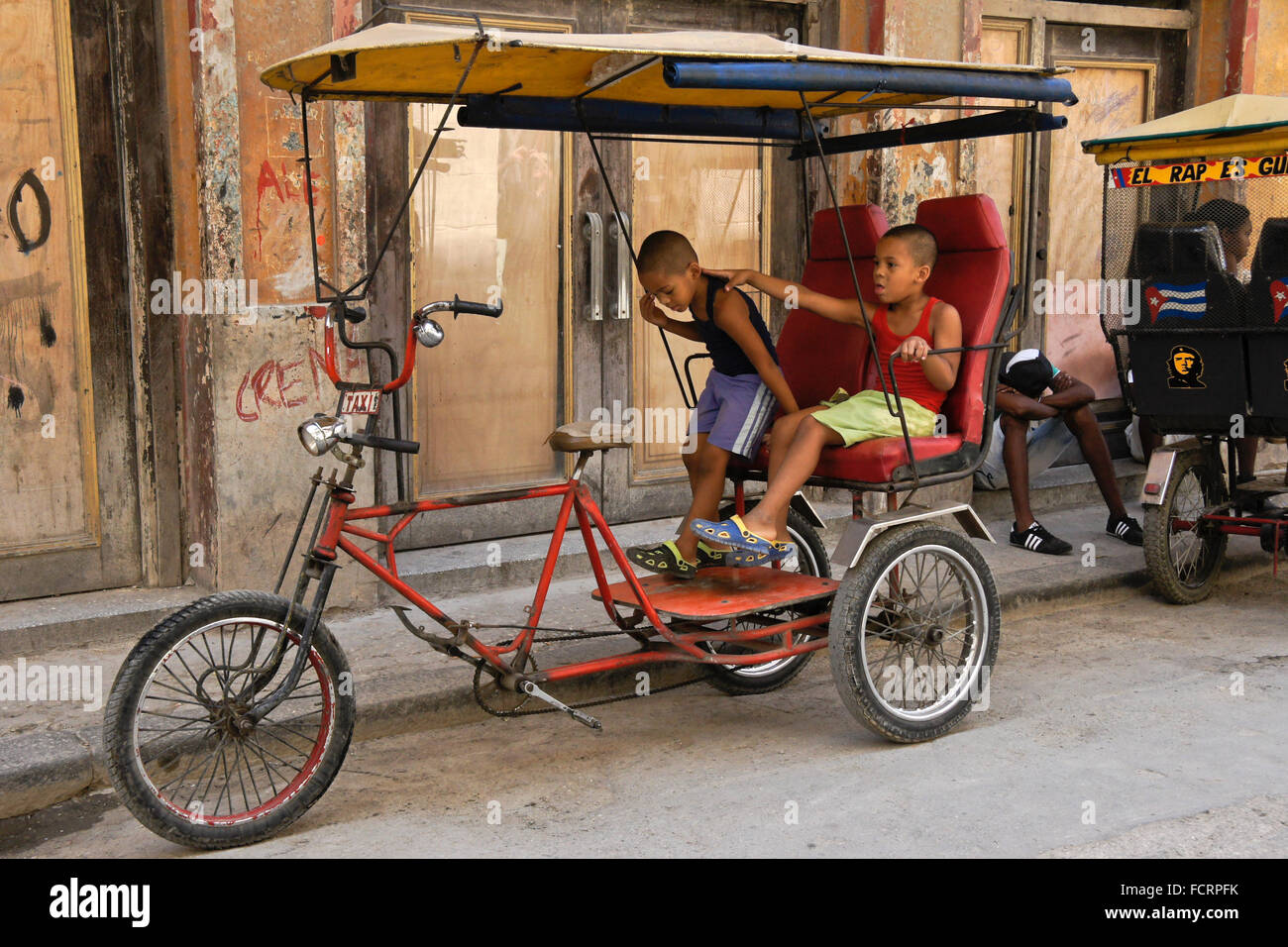 Bambini che giocano su taxi bicicletta, Habana Vieja (l'Avana Vecchia), Cuba Foto Stock
