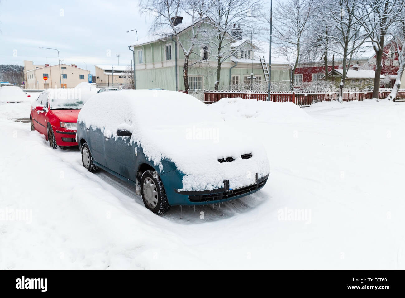 Auto coperti di neve parcheggiato lungo la strada innevata in Finlandia Foto Stock