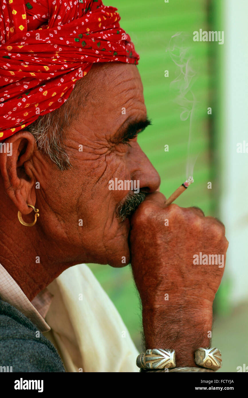 Close-up di un uomo di Rajasthani fumatori bidi, un indiano a mano fatte di sigarette di tabacco o beedi foglie. Fiera di Pushkar, Pushkar, Foto Stock