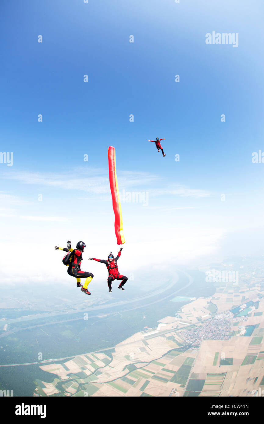 Un pazzo freefly skydiving team sta giocando con un tubo dell'aria in caduta libera insieme. In tal modo la loro caduta con velocità di 120 km/h. Foto Stock