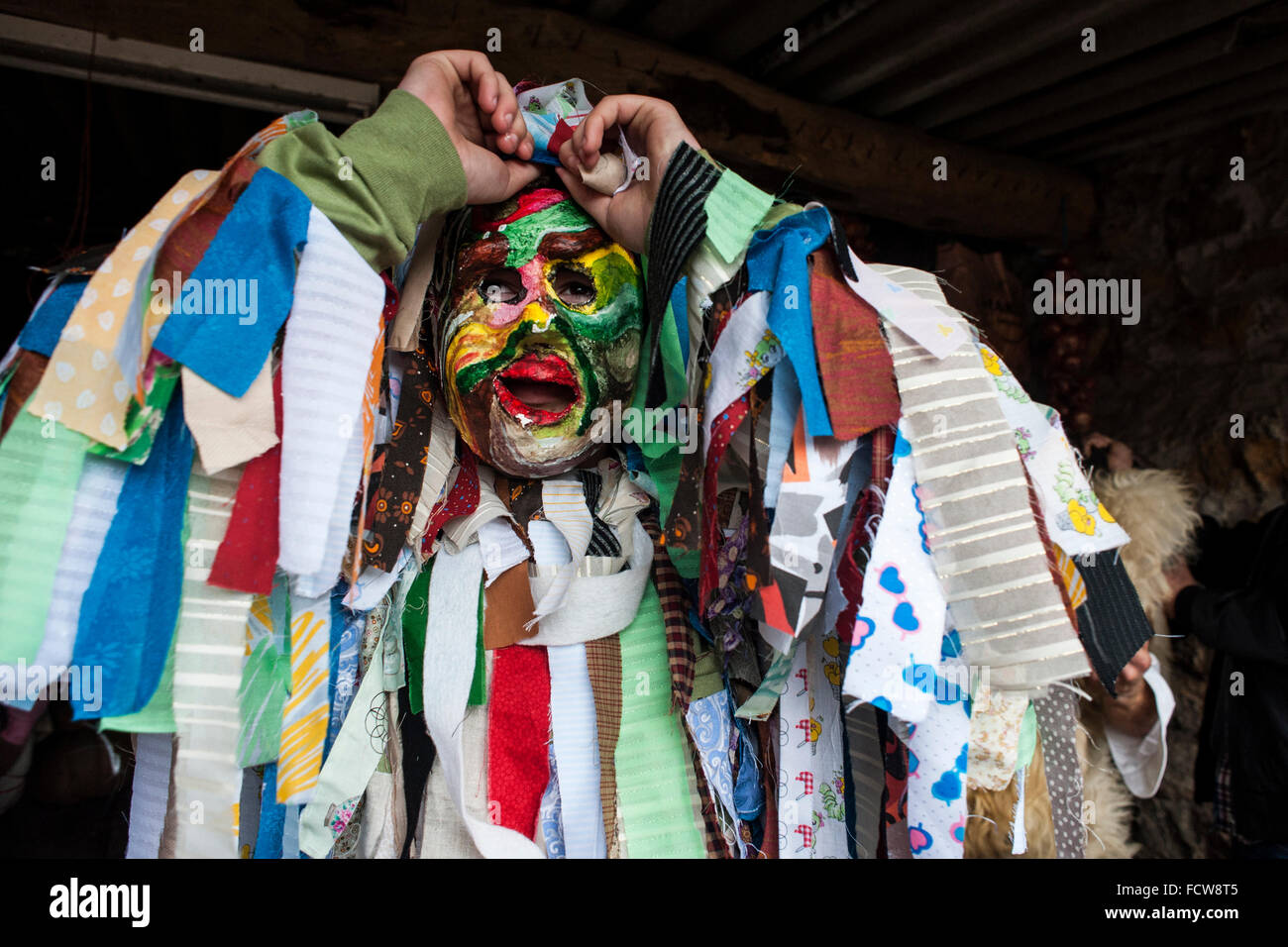 Uno dei trapajones (caratteri i cui costumi sono realizzati con stracci) pone la sua maschera durante il carnevale di La Vijanera in Silio Foto Stock