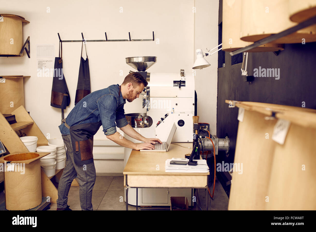 Uomo che utilizza un computer portatile nel moderno spazio di lavoro con macchine Foto Stock
