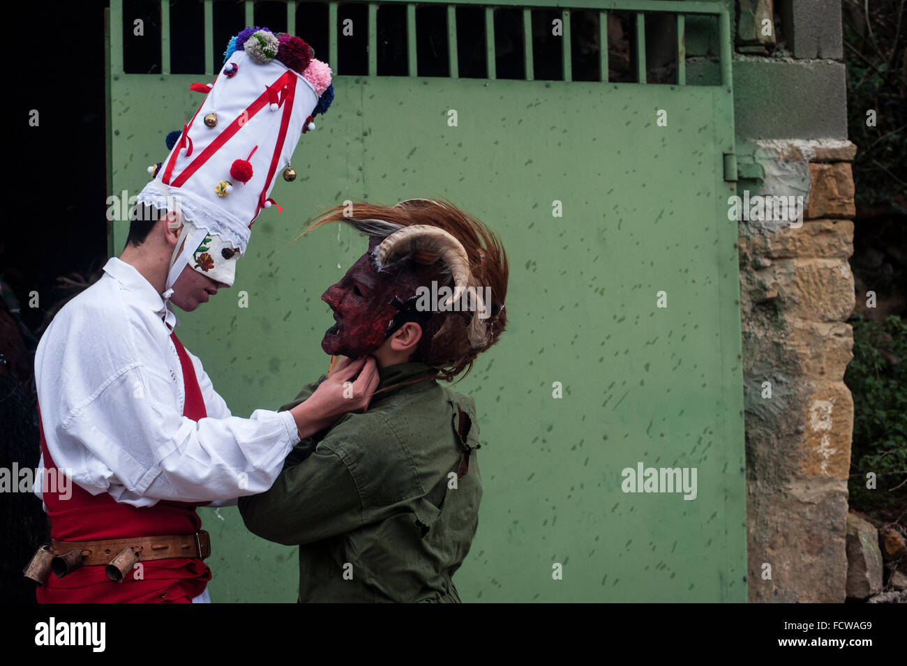 Un bianco Danzarin (un altro carattere carnevale Vijanera) consente a un altro partecipante di legare la maschera. Foto Stock