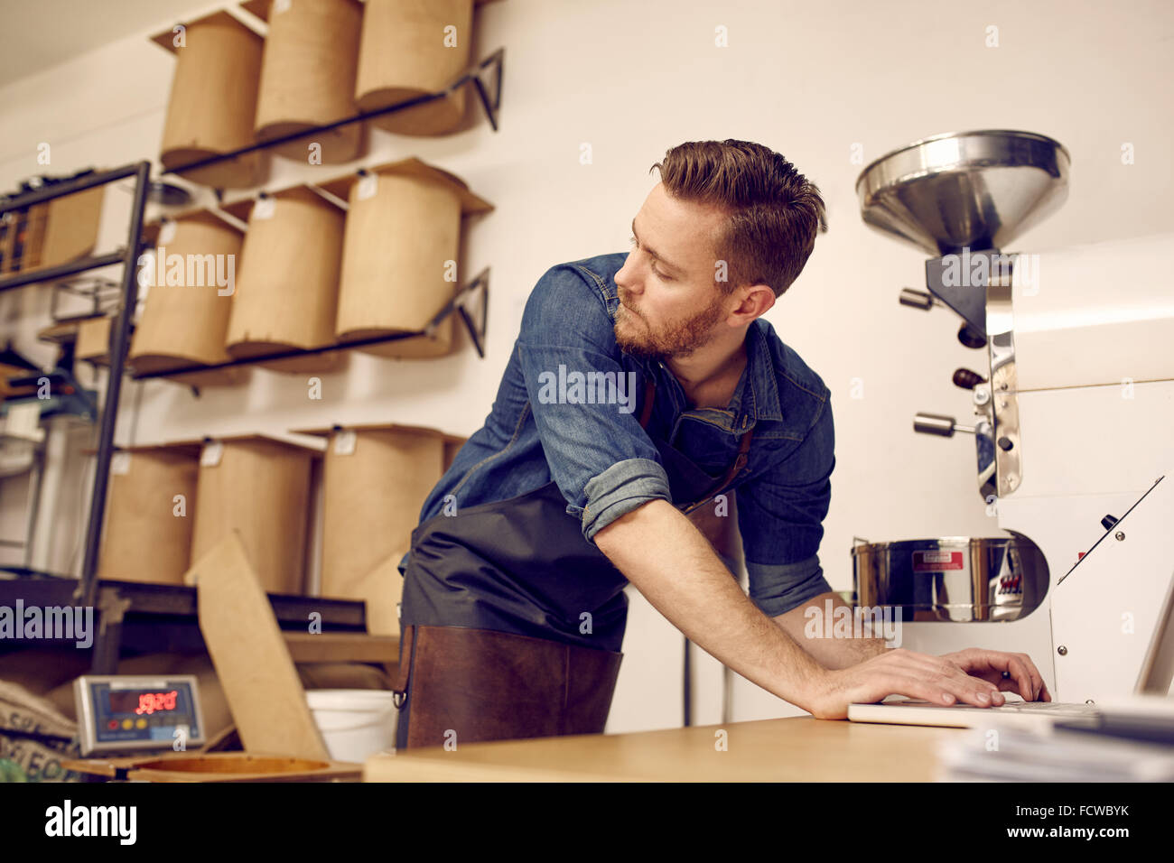 I moderni caffè roastery con il proprietario a lavorare sul suo computer portatile Foto Stock