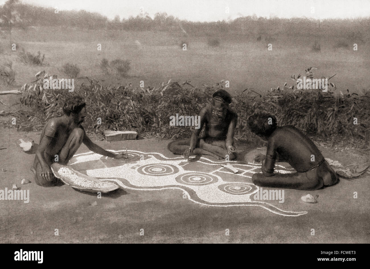 I membri della tribù Warramunga, Australia, preparando un disegno di massa per una cerimonia totemiche. In questo caso la cerimonia è collegato con il serpente nero totem e il profilo ondulato del serpente può essere visto nel disegno incompiuto. Dopo un xix cenutury fotografia. Da usi e costumi del mondo, pubblicato 1900. Foto Stock