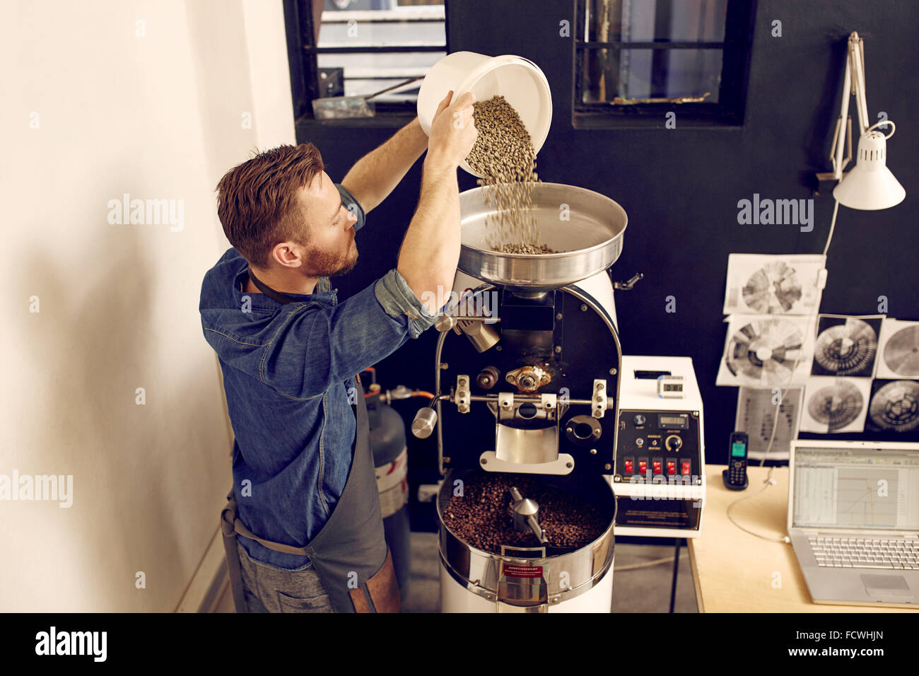 L'uomo versando il caffè crudo fagioli in una moderna macchina Foto Stock