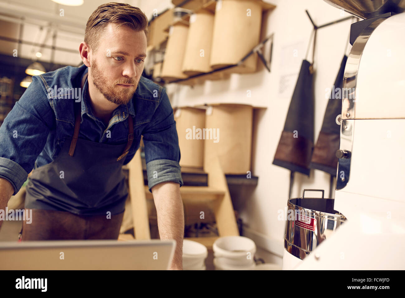 Imprenditore lavorando nel suo ordinato e moderno coffee roastery Foto Stock