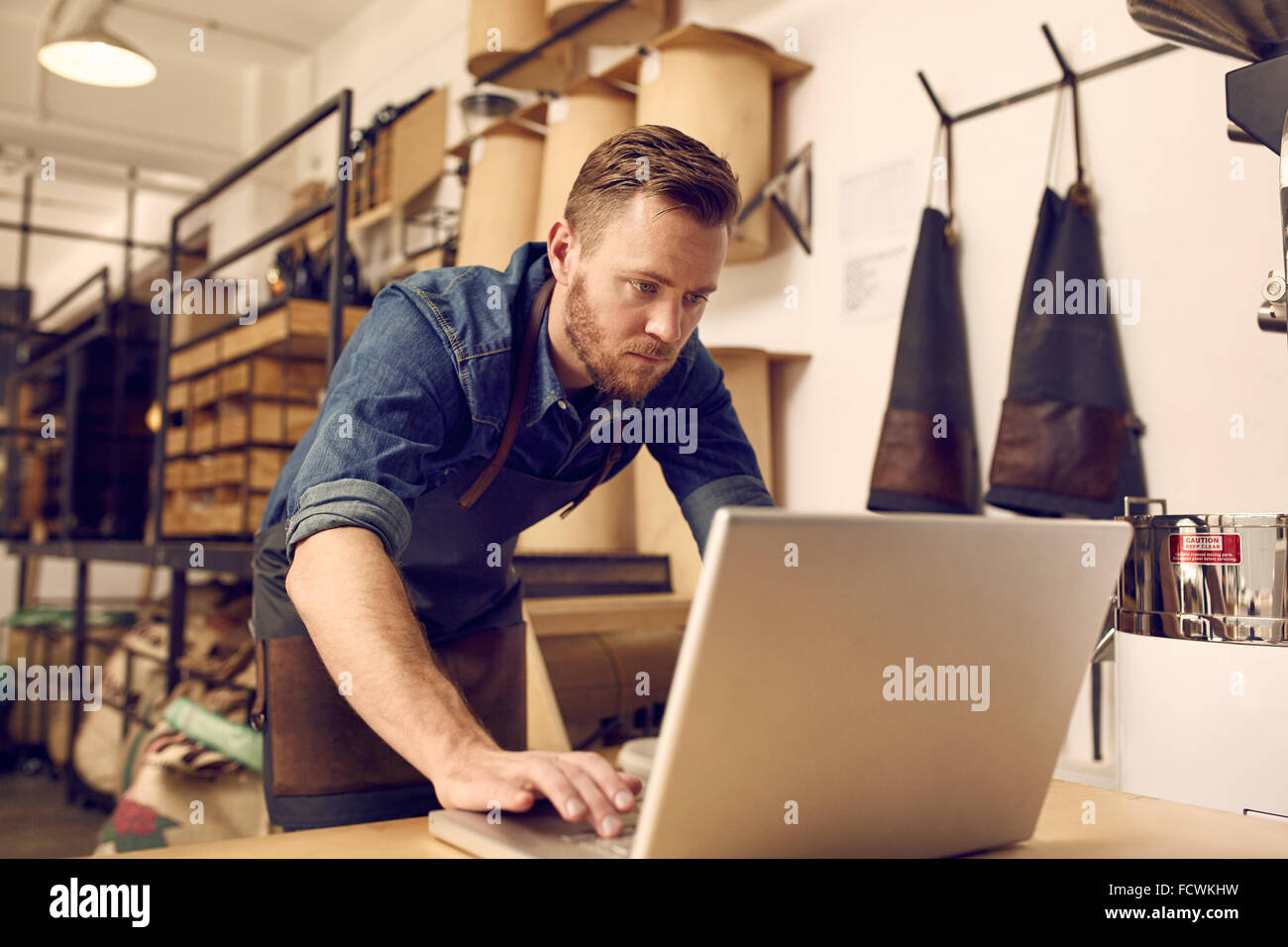Grave giovane proprietario di affari con computer portatile nel suo laboratorio Foto Stock