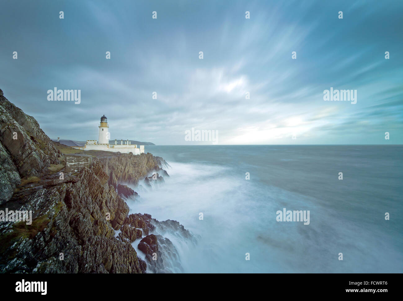 Una lunga esposizione di un mare tempestoso con faro sulla cima delle scogliere rocciose. Posizione, Douglas, Isola di Man, Regno Unito Foto Stock