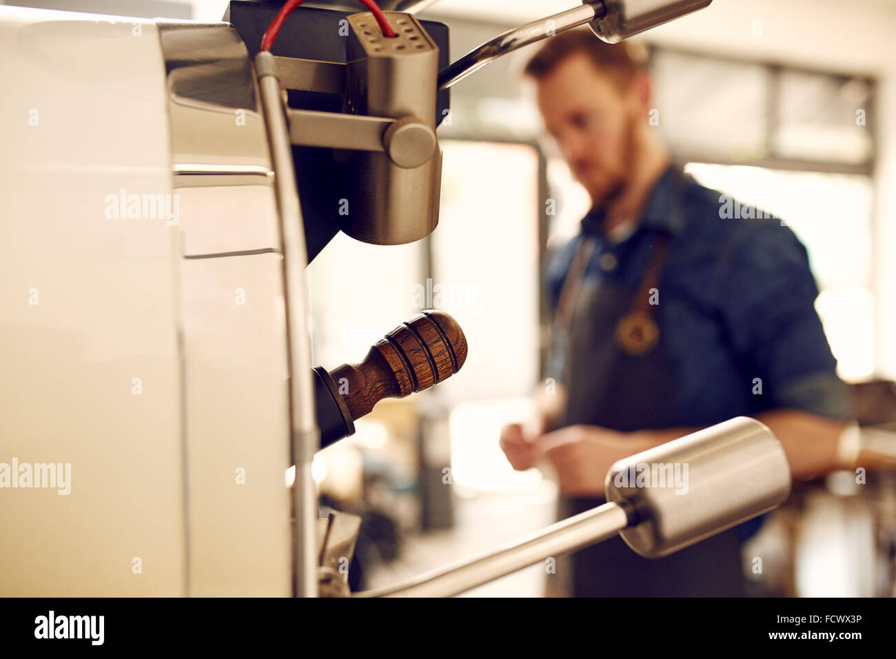 Chicco di caffè tostatura di macchina con uomo sullo sfondo Foto Stock