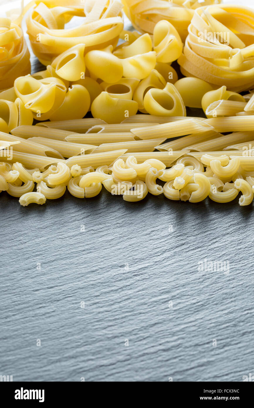 Varietà di tipi e forme di pasta italiana su una pietra scura sullo sfondo. Foto Stock