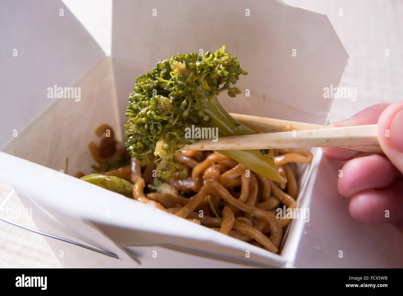 Il cinese estrarre, broccoli detenute con bacchette Foto Stock