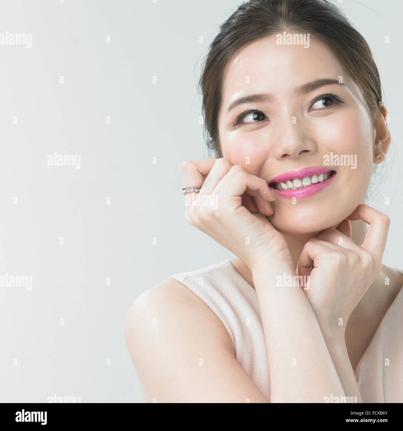 Donna con labbro di rosa per il make-up sorridente con le mani attorno al suo viso Foto Stock