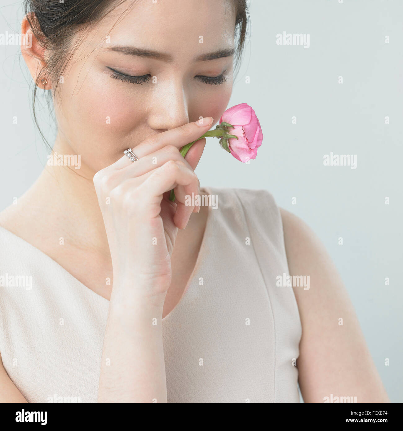 Donna odorare una rosa con gli occhi chiusi Foto Stock